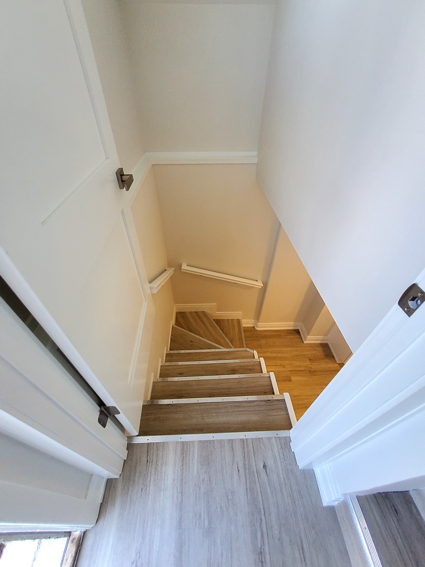 Basement stairwell after remodel: white walls, finished trim, hardwood treads