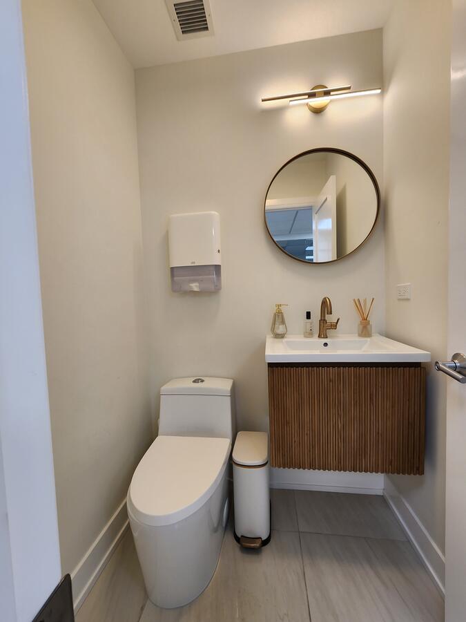 Designer restroom with round mirror and gold fixtures